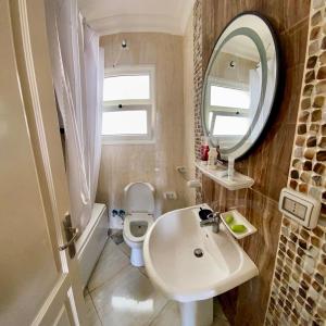 Un baño con lavabo, inodoro y espejo. en Madinaty Hotel, en Madinaty 8 fotos más