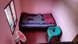 a small room with a bed and a blue chair at Kyathanamakki Base Camp Stay in Kalasa