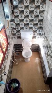 a bathroom with a toilet in a room with tiles at Kyathanamakki Base Camp Stay in Kalasa