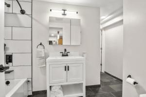 a white bathroom with a sink and a mirror at BRAND NEW Private and Modern 2BR Unit in Minneapolis