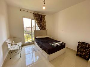Un dormitorio con una cama y una ventana y una silla. en Madinaty Hotel, en Madinaty