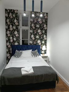 a bedroom with a blue bed with floral wallpaper at Tabago Studio 16 in Nysa