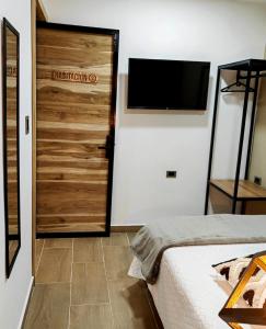 een slaapkamer met een bed en een televisie aan de muur bij Cálida Habitación privada a 20 mt del parque in Salento