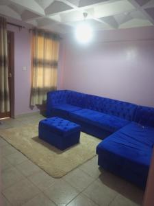 a living room with a blue couch and ottoman at Verona Apartments in Thika