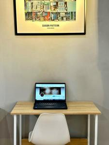 - un ordinateur portable assis sur une table en bois avec une chaise blanche dans l'établissement Stay&Chill S.6 - Tranquil home in Saigon's heart, à Hô-Chi-Minh-Ville