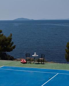 two chairs and a table on a tennis court at OLYN VILLAS in Nikiti