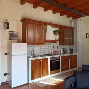 cocina con armarios de madera y nevera blanca en La casetta di Elly, en Puegnago sul Garda