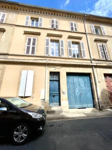 une voiture noire garée devant un bâtiment avec portes bleues dans l'établissement Appartement le Regnaudin, à Moulins