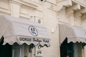 Giorgio Boutique Hotel في سليمة: مبنى عليه مظلة بيضاء على محل