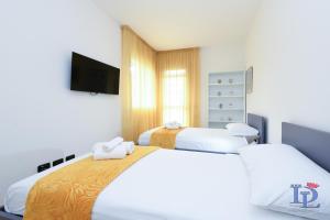 Dos camas en una habitación con un televisor en la pared. en Marriott The Wind Rose renovation 2025 DesenzanoLoft Official Partner Homes & Villas by Marriott Bonvoy, en Desenzano del Garda