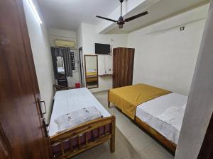 a bedroom with two beds and a ceiling fan at Raja Rani Mahal Ac-Rooms in Tiruvannāmalai