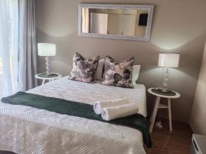 a bedroom with a bed with two lamps and a mirror at Zhantique Guest House Unit 5 in Boksburg