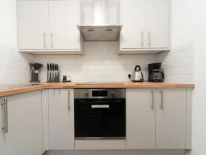 una cucina con armadietti bianchi e lavastoviglie nera di Pass the Keys Spacious Wembley Apartment with Free Parking a Londra