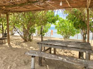 a wooden bench sitting under a pavilion on the beach at Talim Camp n Sea Beach Camp in Lian