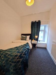 a bedroom with a bed and a window at SleepyStays 3 Bedroom Modern & Central Location Sleeps 4 in Merthyr Tydfil