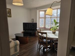 a living room with a table and a television at 4 Bedroom Home with Parking in Luton