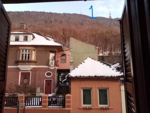 a house with snow on the roof and a blue flag at Old Town Studio in Braşov