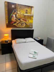 Residencial Brest Amazon Tarapoto في تارابوتو: سرير في غرفة مع لوحة على الحائط