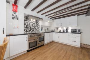 a large kitchen with white cabinets and an oven at Seaview on the beach in Port Erin
