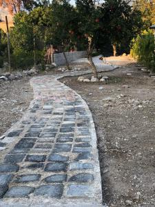 einen Kopfsteinpflasterweg in einem Garten mit einem Baum in der Unterkunft Nar Bahçesi in Çakırlar