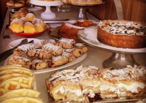 a table with many different types of pastries and pies at Pousada Cheverny - Fácil acesso ao centrinho e Baden Bar in Campos do Jordão