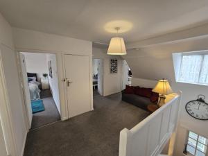 uma sala de estar com uma escada e um relógio na parede em Beautiful 4 bedroom house 7 minutes from Luton Airport em Luton