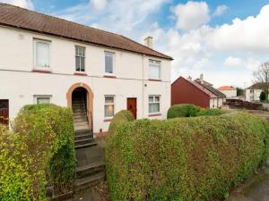 a white house with bushes in front of it at Pass the Keys Spacious Murrayfield Flat in Edinburgh