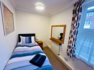 a bedroom with a bed and a mirror and a window at Cosy Victorian Apartment - Central York in York