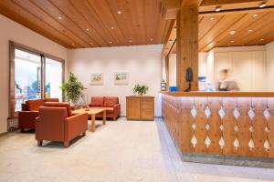 a lobby with a waiting area with chairs and a counter at Hotel Grindelwalderhof in Grindelwald