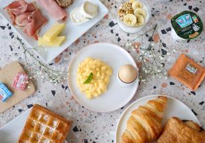 una mesa cubierta con platos de comida, huevos y pan en Appart'City Confort Toulouse Diagora Labège, en Labège