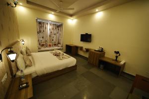 a bedroom with a bed and a window and a television at The Kumbha Mahal Resort in Kumbhalgarh