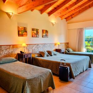 a hotel room with two beds and a suitcase at Posada La Soñada in Villa General Belgrano