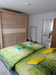 Apartman D في فيشغراد: غرفة نوم بسريرين مع شراشف خضراء ومخدات صفراء