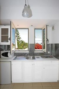 a kitchen with a sink and two windows at Oliv Apartments in Platanes