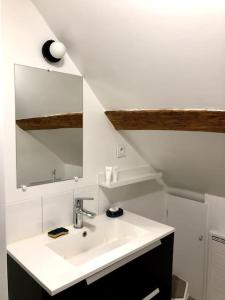 a white bathroom with a sink and a mirror at maison de ville agréable La roseraie Musicale in Mer