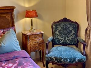 a bedroom with a chair and a lamp next to a bed at Chateau Masburel in Fougueyrolles