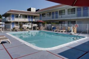 uma piscina num hotel com cadeiras e um edifício em Motel 6-Springfield, OR - Eugene North em Springfield