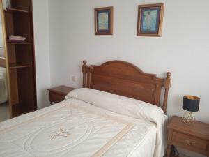 um quarto com uma cama com lençóis brancos e duas mesas em Mar de Gala em Suances
