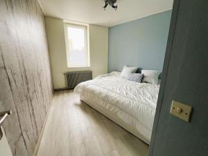 a bedroom with a bed with white sheets and a window at Appartement l'effet Mers in Mers-les-Bains