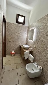 ein Badezimmer mit einem Waschbecken, einem WC und einem Waschbecken in der Unterkunft Standard Room in Pulsano