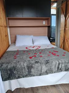 a bed with red roses on it in a bedroom at Tiny House no Olival in Pelotas
