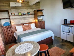 a bedroom with a bed and a table in a room at La Roca Studio 6 in Praia do Rosa