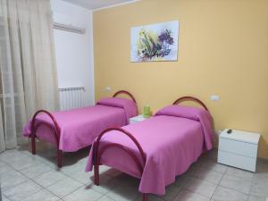 2 Betten in einem Zimmer mit rosa Decken in der Unterkunft Caracciolo B&B in Fiano Romano