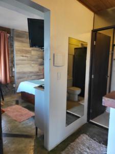 een kamer met een bed en een badkamer met een spiegel bij La Roca Studio 6 in Praia do Rosa