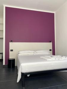 a bedroom with a white bed with a purple wall at AMARENA B&B Porto Recanati in Porto Recanati