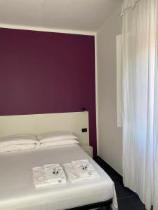 a bedroom with a white bed with a purple wall at AMARENA B&B Porto Recanati in Porto Recanati