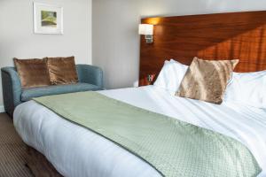 um quarto de hotel com uma cama grande e uma cadeira em Clarion Hotel Newcastle South em Sunderland
