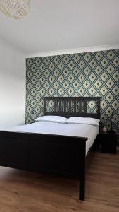 een bed met een zwart bedframe en een muur bij Home Sweet Home (Townhouse) in Manchester