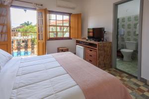a bedroom with a bed and a television and a bathroom at Pousada Neuza Barbosa in Tiradentes +133 photos