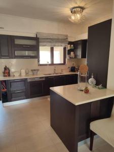 une cuisine avec des armoires noires et un comptoir blanc dans l'établissement Sophie's Cozy House, à Patras